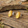 Gold stud earrings on a wooden surface with a stone background
