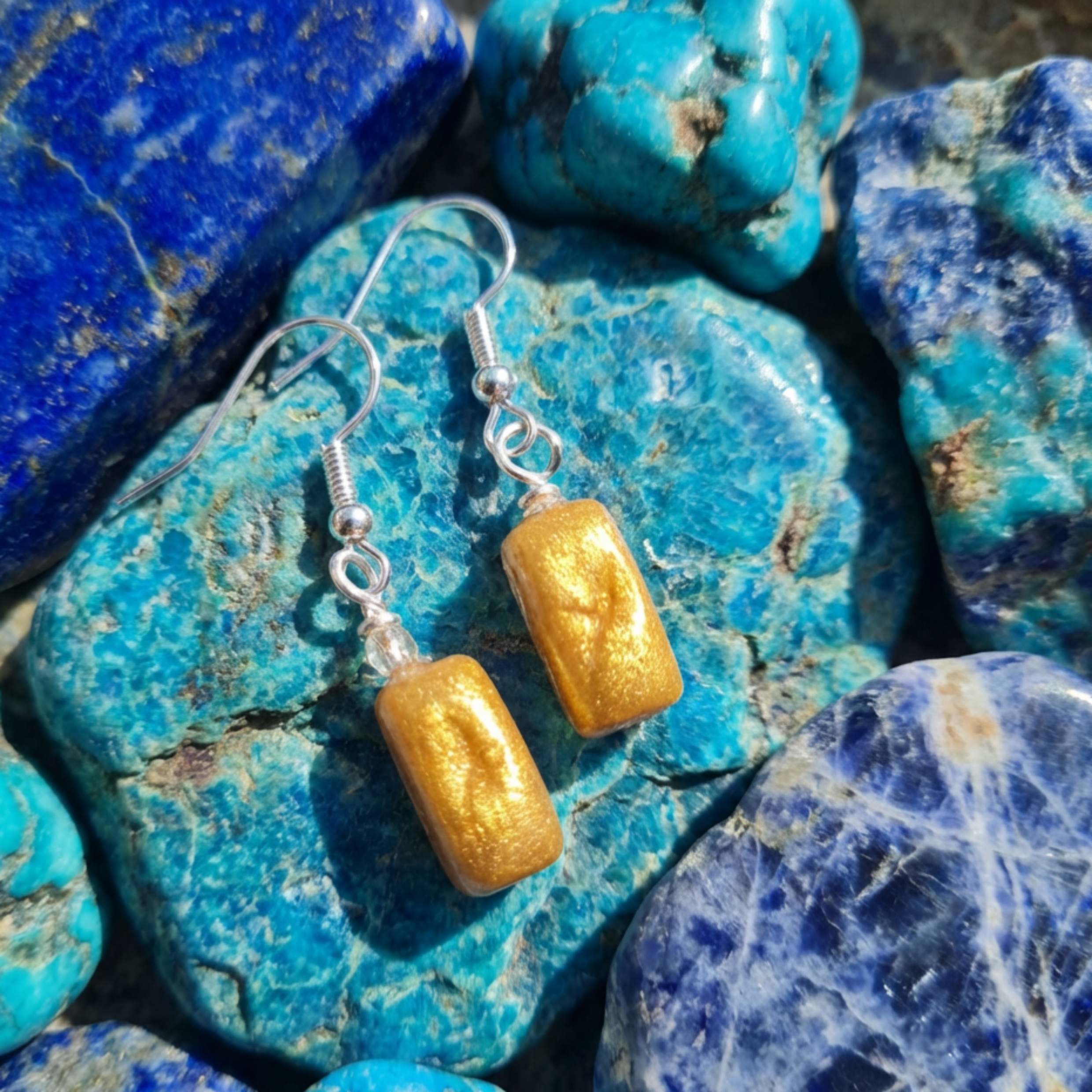 Gold rectangle drop dangle earrings on a blue stone