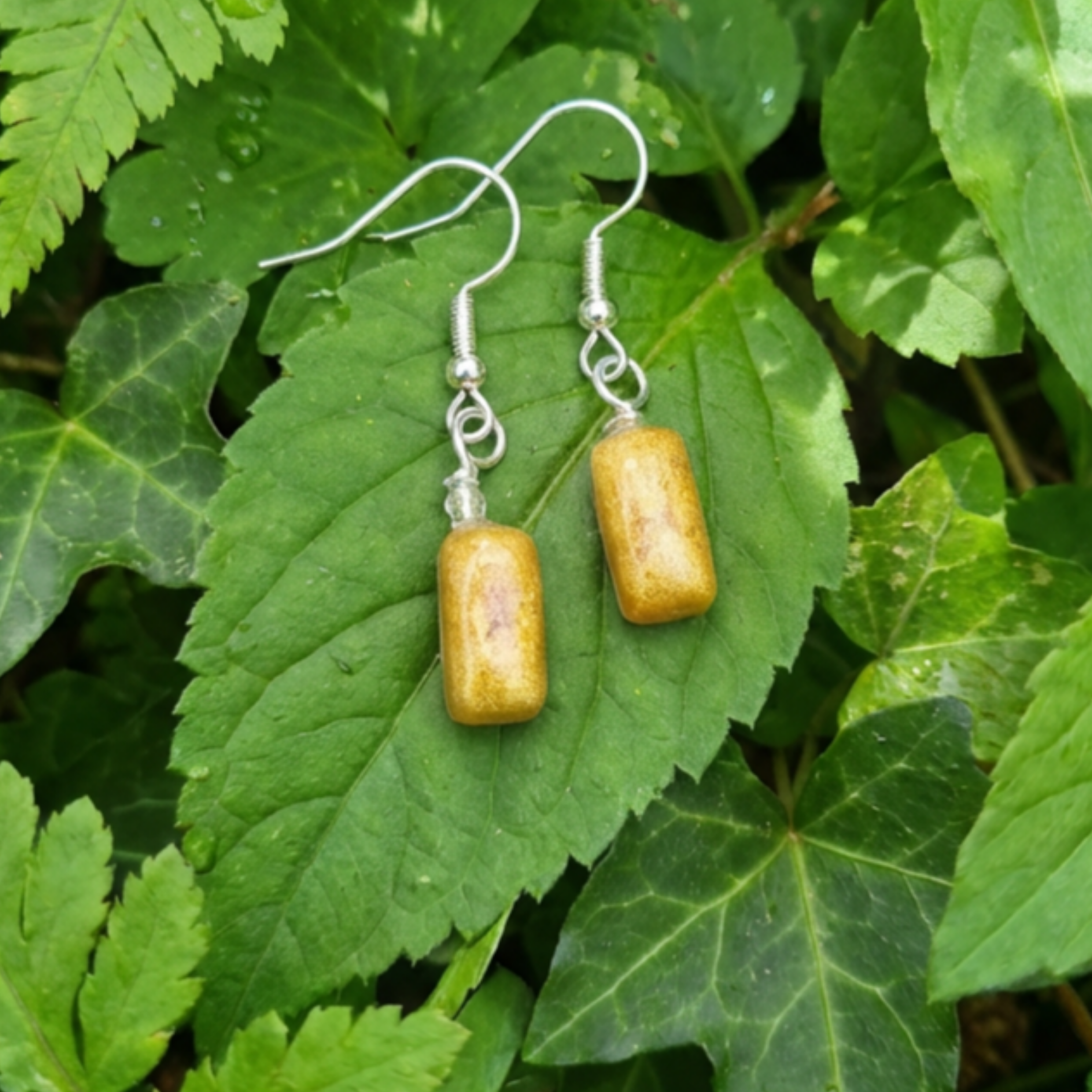 Simple rectangle gold drop earrings on a leaf