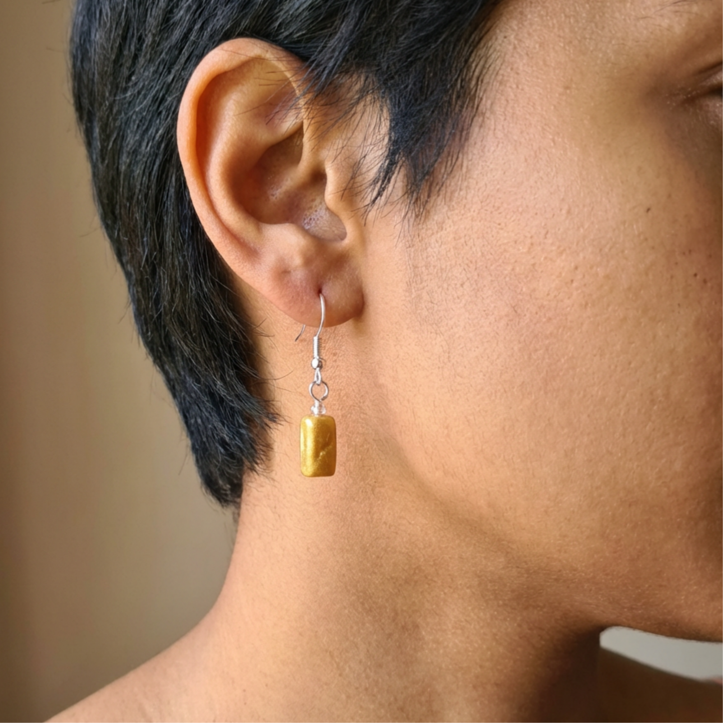 Gold rectangle drop earrings worn by a woman