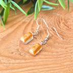Gold rectangle shimmer earrings on a wooden surface