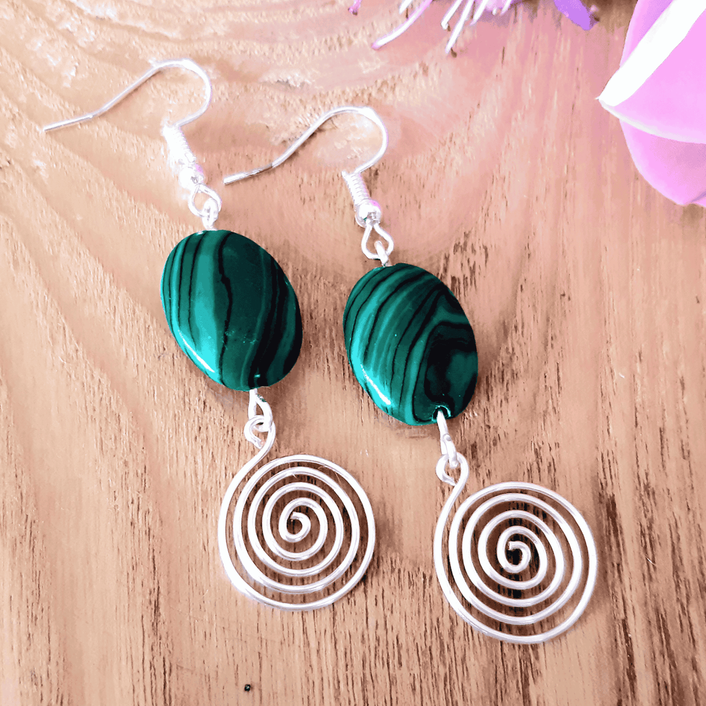 Green marbled earrings with spiral designs on a wooden surface