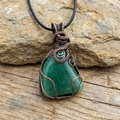 Green Aquamarine stone pendant with copper wire wrapping on a rock background