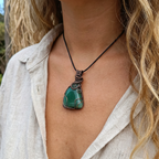 Person wearing a necklace with a green pendant outdoors