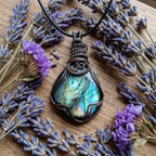 Labradorite pendant necklace surrounded by dried lavender flowers on a wooden surface