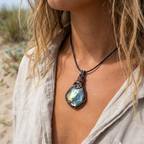 Person wearing a necklace with a large labradorite pendant outdoors