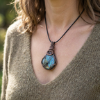 Necklace with a Labradorite pendant worn by a person in a green sweater.
