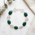 Bracelet with green beads and silver spiral accents on a marble surface