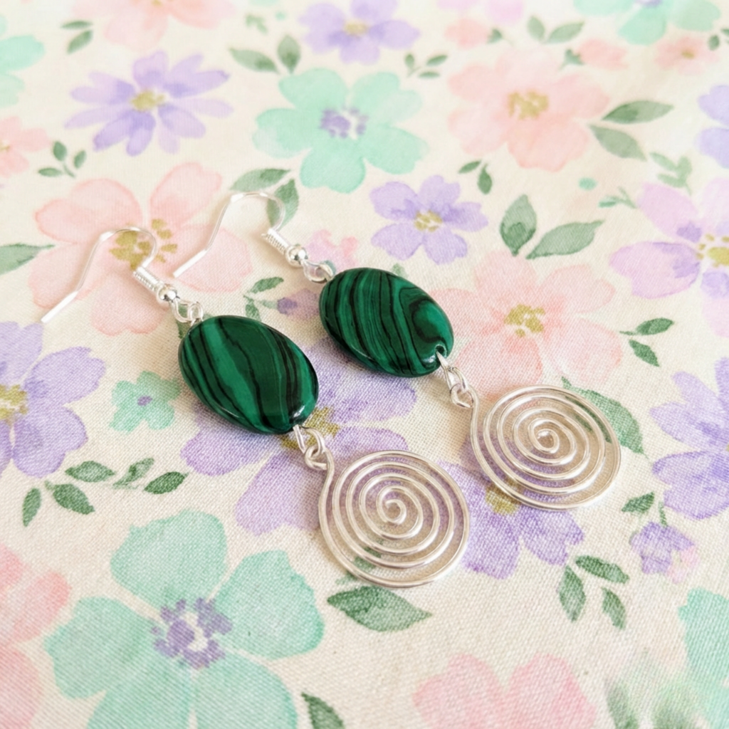 Pair of earrings with green marbled stones and silver spiral designs on a floral background