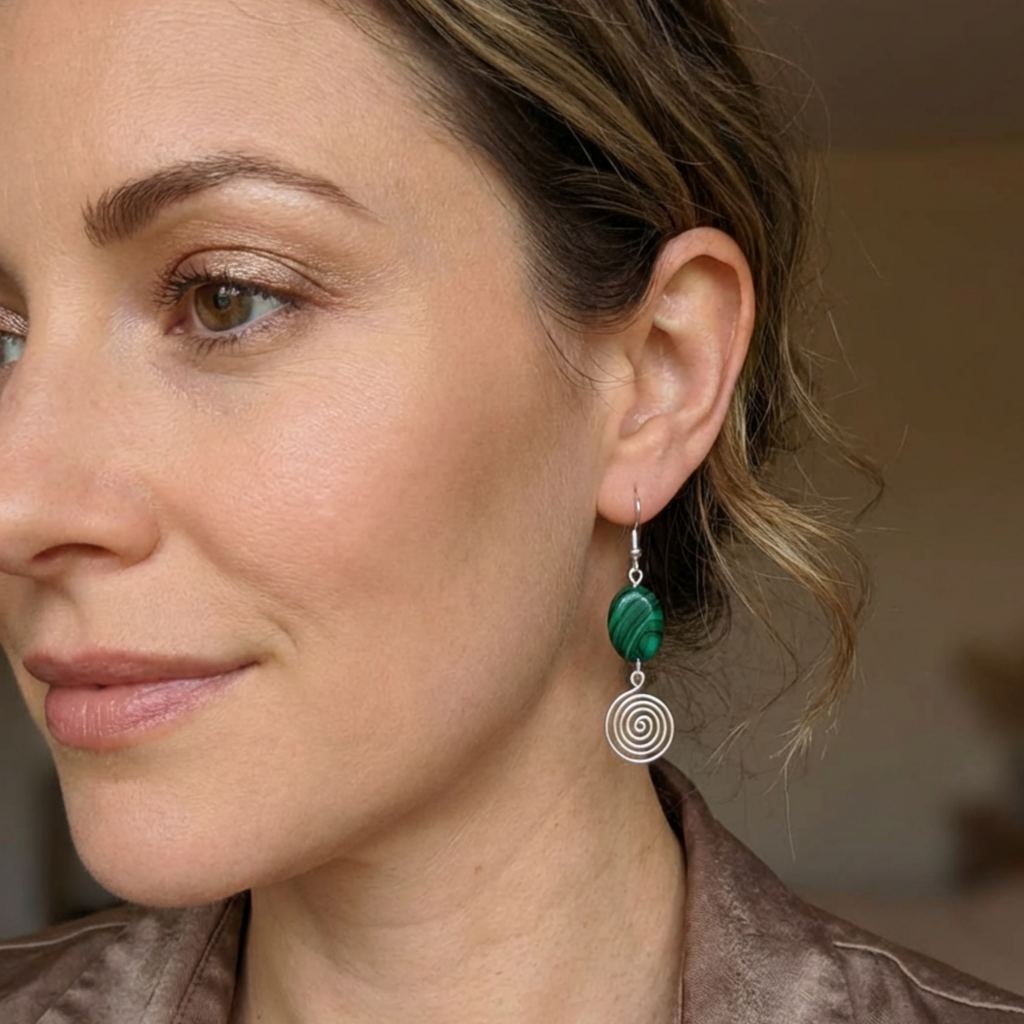 Close-up of a woman wearing green and silver earrings with a blurred background