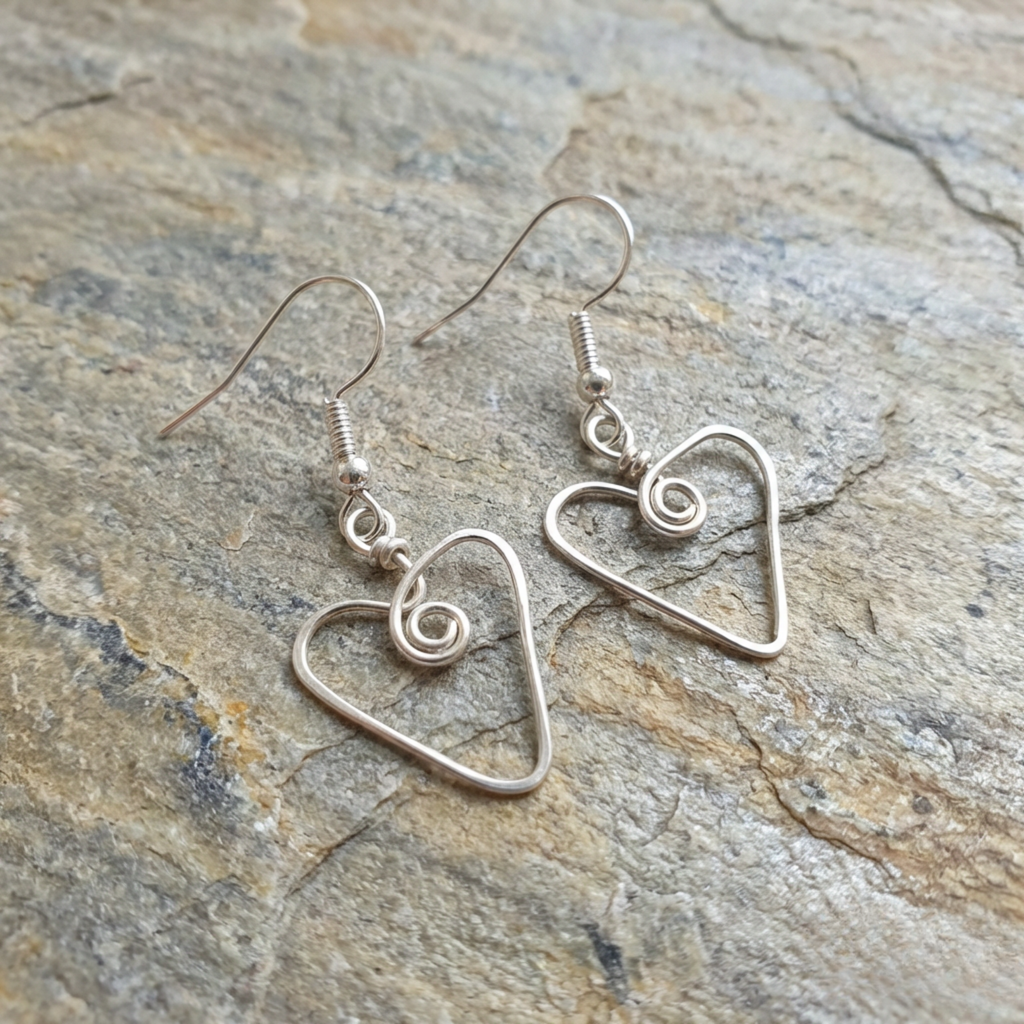 Silver heart-shaped earrings on a stone surface