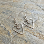 Silver heart-shaped earrings on a stone surface