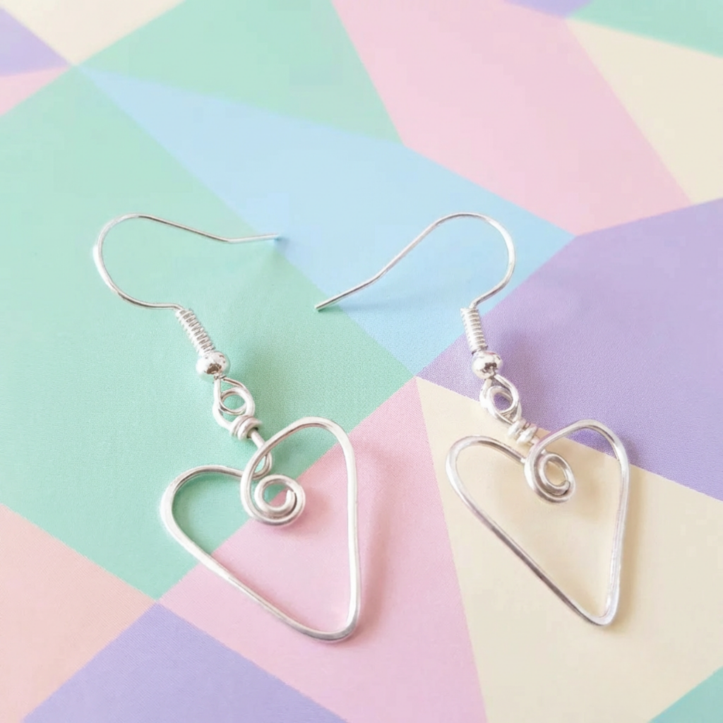 Heart-shaped silver earrings on a colorful geometric background