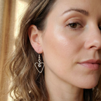 Close-up of a woman wearing a heart-shaped earring with a blurred background