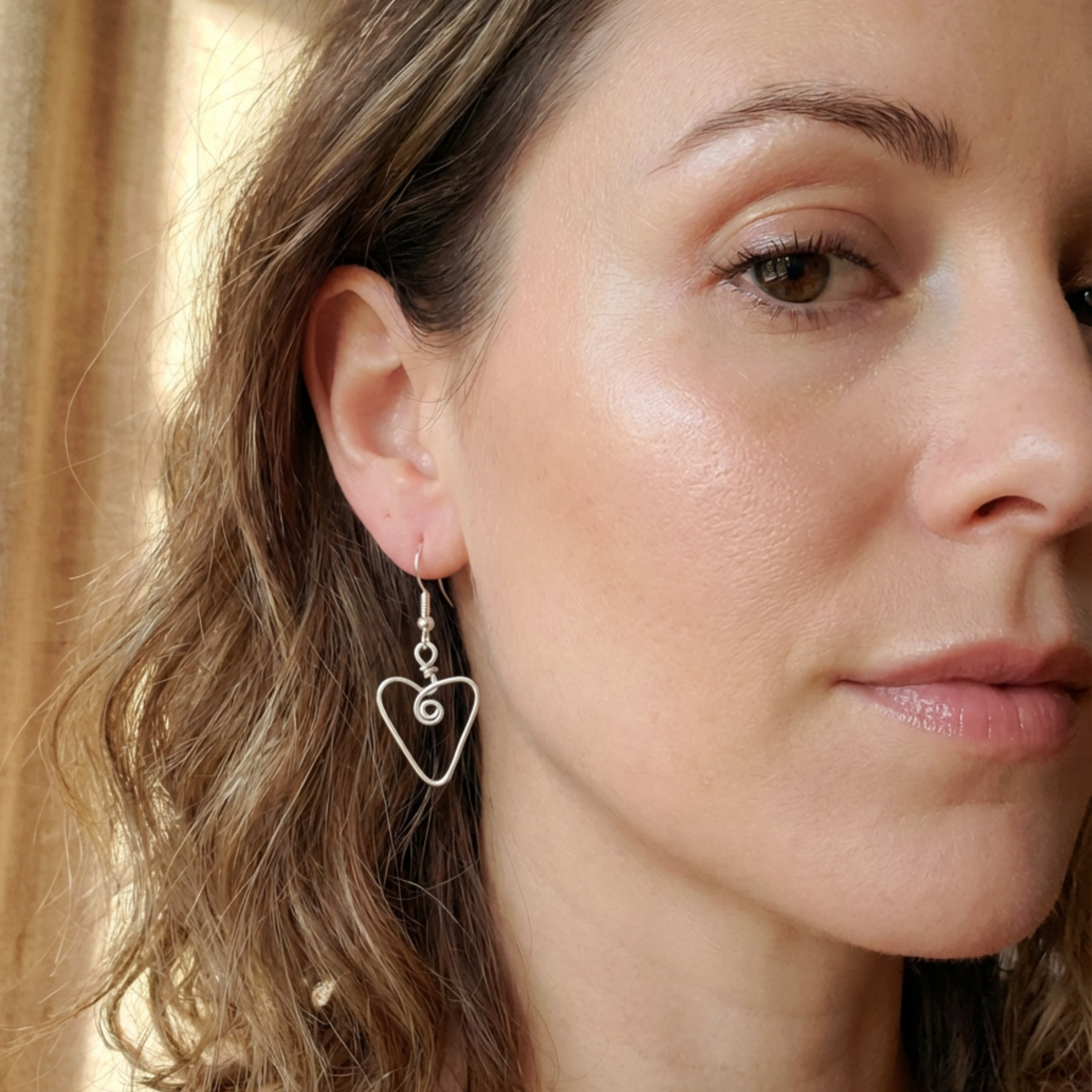 Close-up of a woman wearing a heart-shaped earring with a blurred background