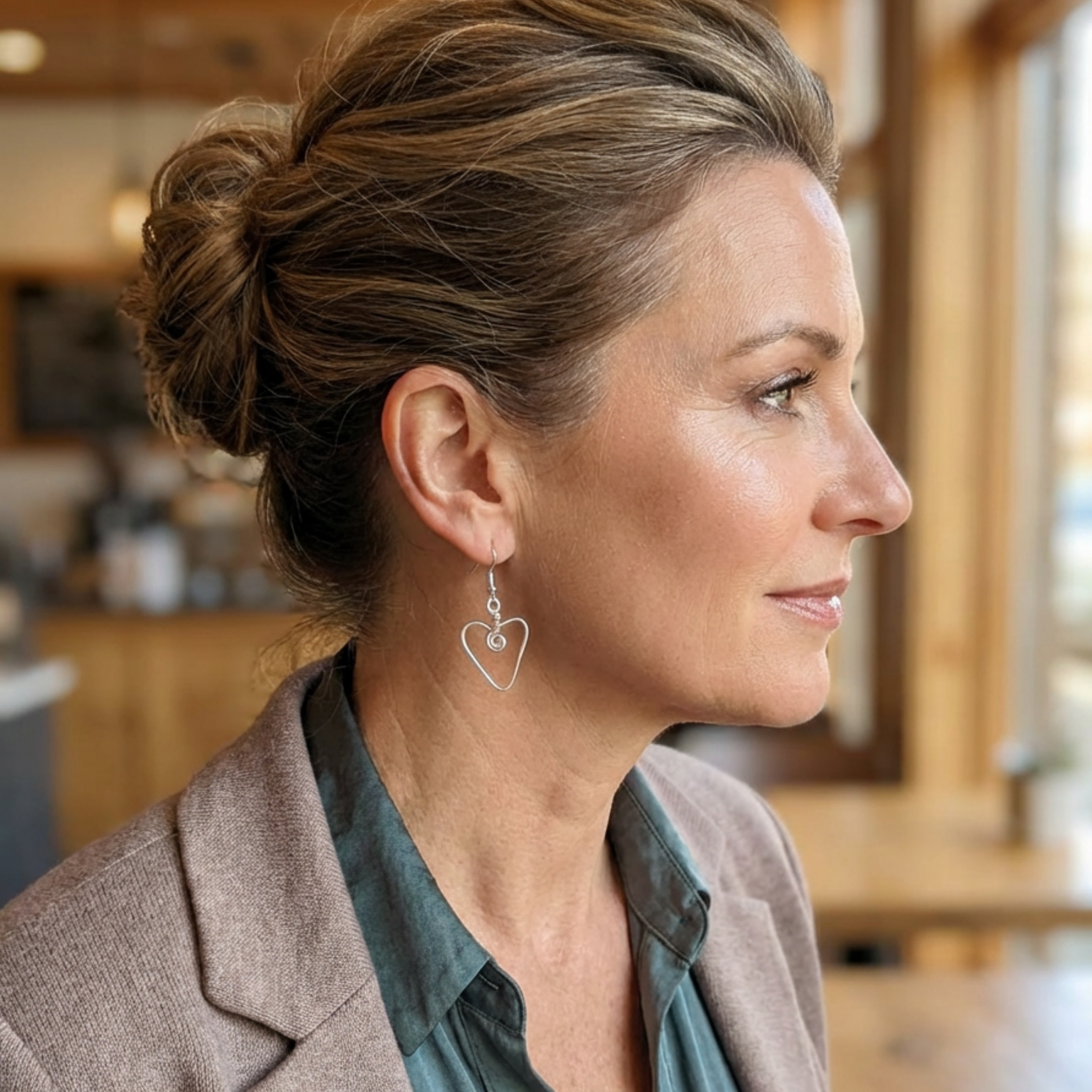 Woman wearing heart-shaped earrings in a blurred indoor setting