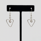 Heart-shaped earrings on a black earring stand against a white background