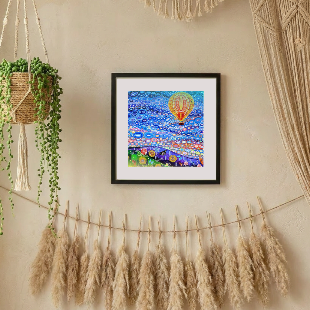 Framed artwork with a hot air balloon and floral design, hanging on a wall with decorative elements.