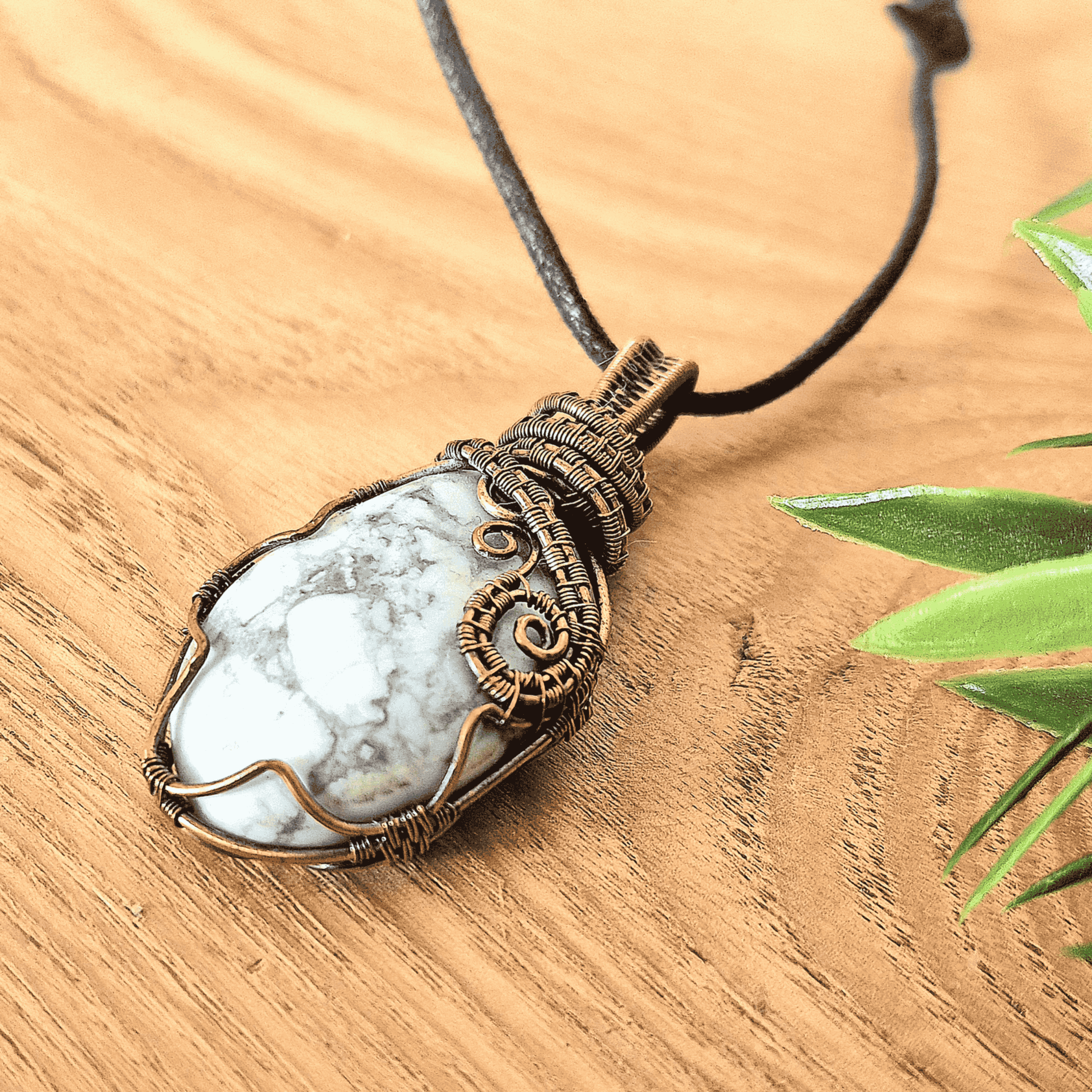 Necklace with a pendant featuring a white stone and bronze wire wrapping on a wooden surface.