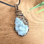 Pendant with white and grey marbled Howlite stone and bronze wire wrapping on a wooden surface