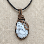 Necklace with a pendant featuring a white stone and copper wire wrapping on a beige fabric background