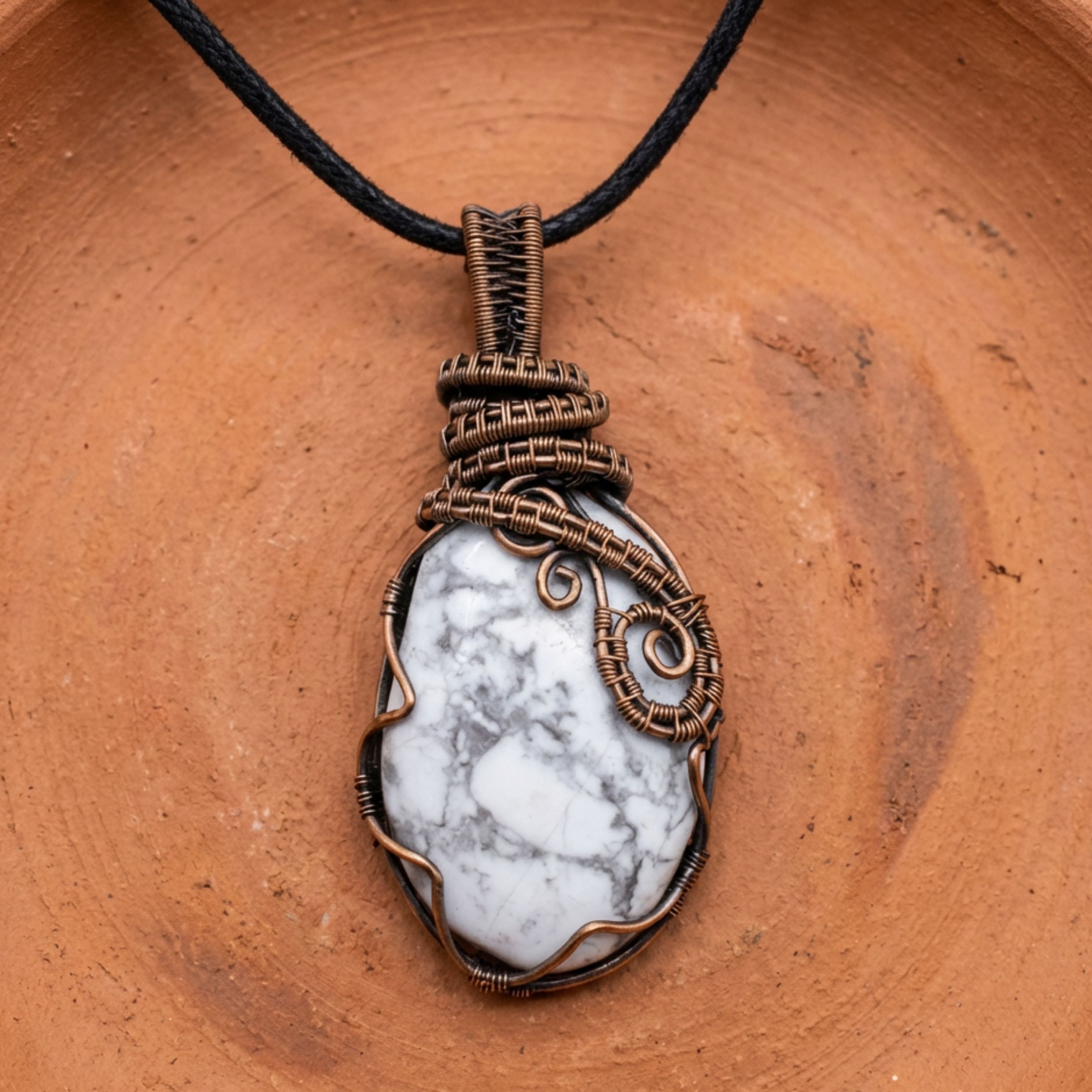 Pendant with white stone and bronze wire wrapping on a brown surface