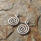 Silver spiral earrings on a stone surface