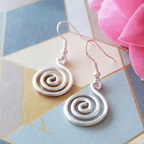 Silver spiral earrings on a colorful geometric background