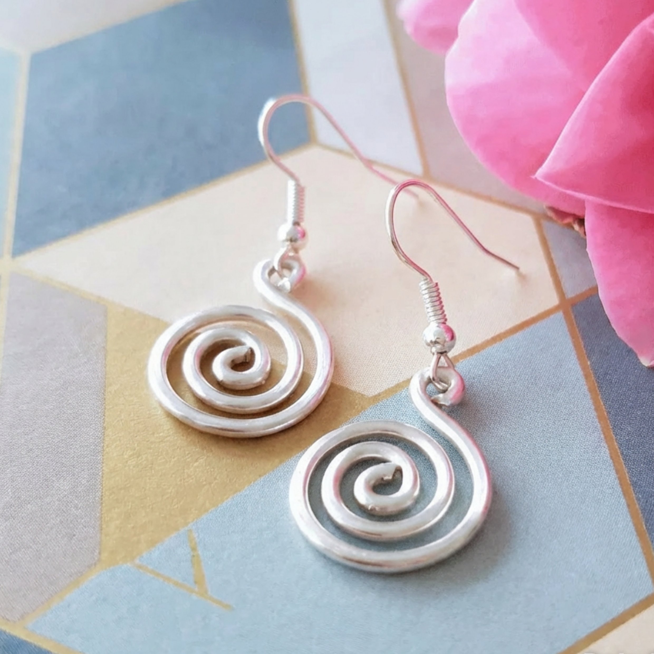 Silver spiral earrings on a colorful geometric background
