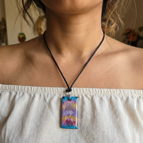 Person wearing a necklace with a colorful pendant, blurred background
