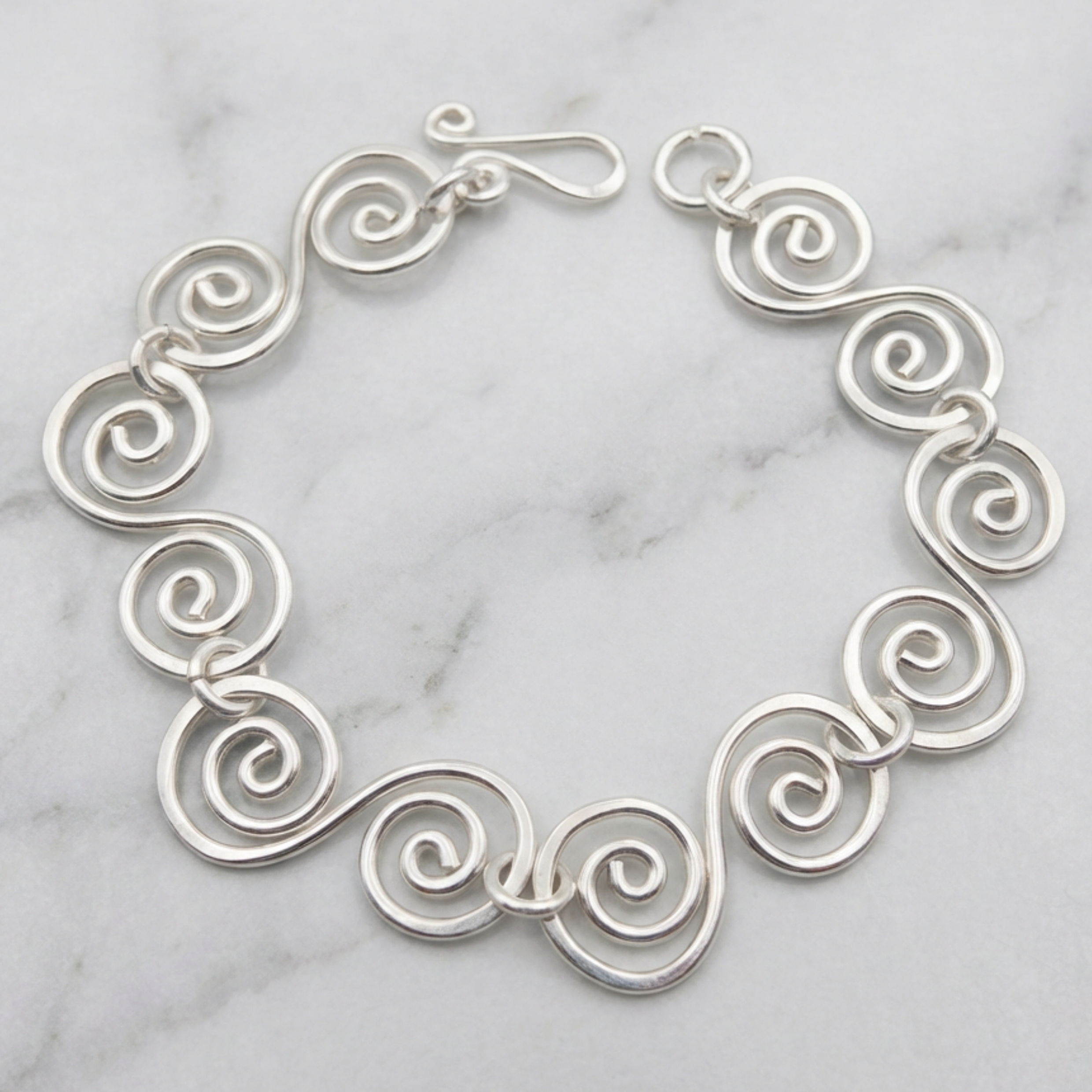 Handmade silver spiral bracelet on a marble surface