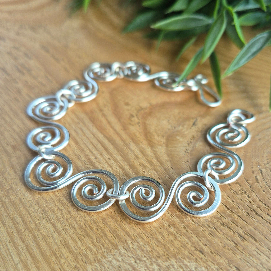 Angled view of a large Celtic S shaped spiral bracelet showing the thickness of the wre