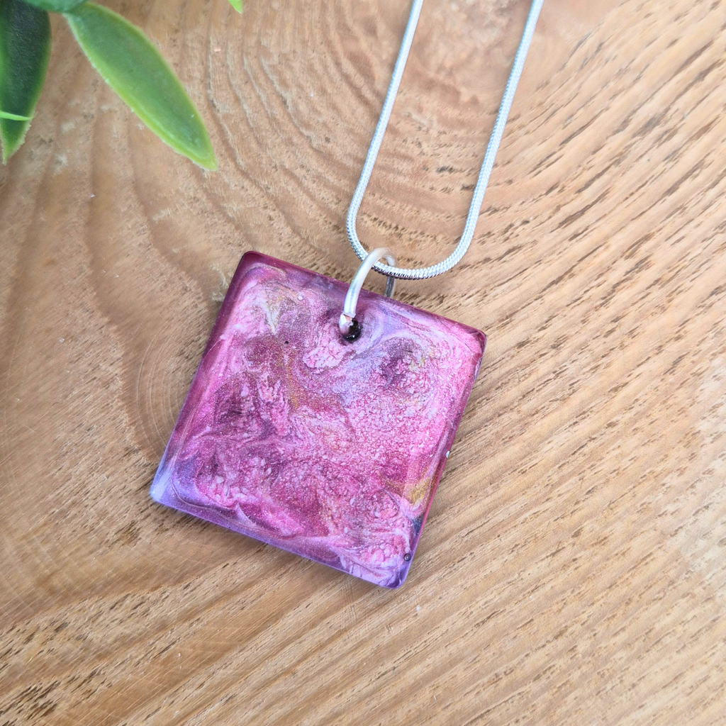 Pink square pendant necklace on a wooden surface