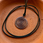 Spiral pendant necklace on a black cord against a terracotta background