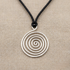 Silver spiral pendant on a black cord against a beige fabric background