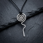 Silver spiral pendant on a black cord against a dark stone background