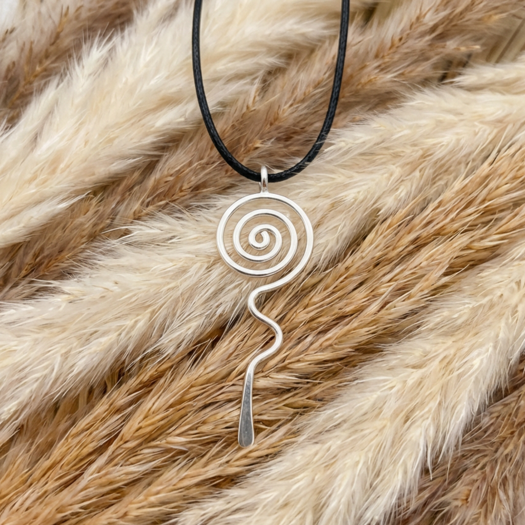 Silver spiral pendant on a black cord against a fur background