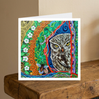 Colourful greeting card with an owl design on a wooden surface.