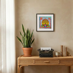Decorative setup with a potted plant, typewriter, and framed artwork on a wooden console table.