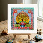Colourful abstract artwork on a small easel with decorative stones on a wooden surface.