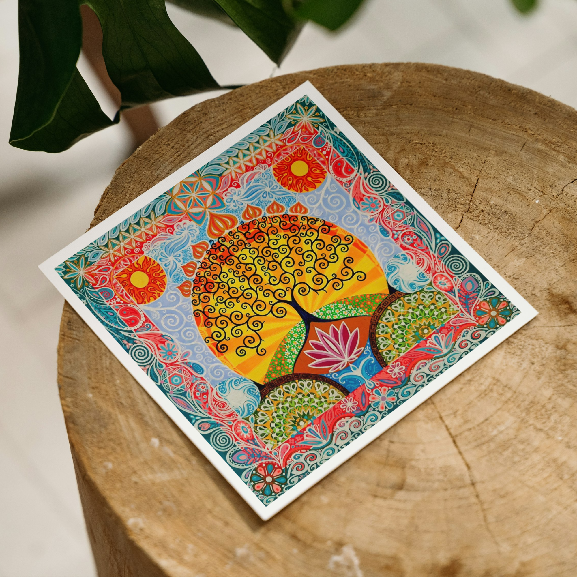 Colorful mandala-style artwork on a wooden surface with green leaves in the background