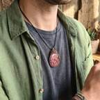 Male model wearing a copper wire wrapped Rhodonite pendant with flowers