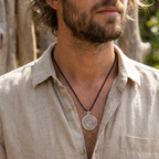 Man wearing a beige shirt with a spiral pendant necklace outdoors