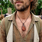 Man wearing a necklace with a large red jasper pendant outdoors
