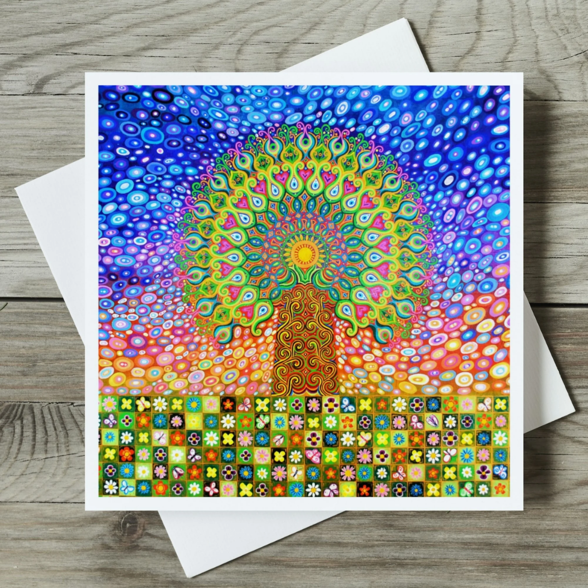 Colourful abstract Tree of Life Mandala design card with a white envelope on a wooden surface