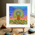 Colourful mandala Tree of Life art on a small easel with decorative stones on a wooden surface.