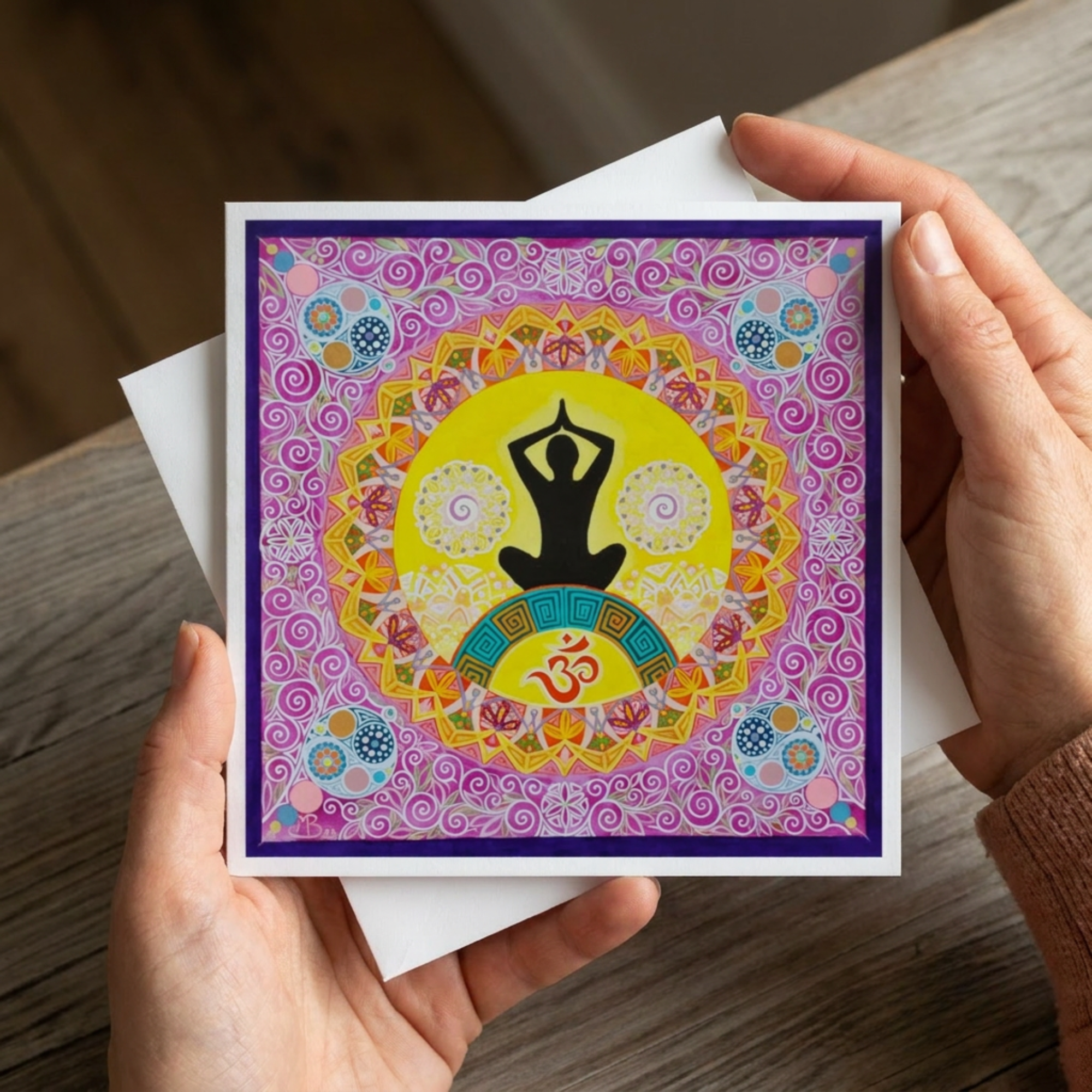 Colourful card with yoga pose and Om symbol held by hands on a wooden surface