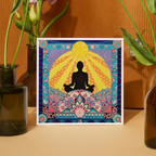 Colorful framed artwork of a meditating figure with floral patterns on a wooden surface.