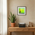 Decorative setup with a potted plant, typewriter, and framed artwork on a beige wall.