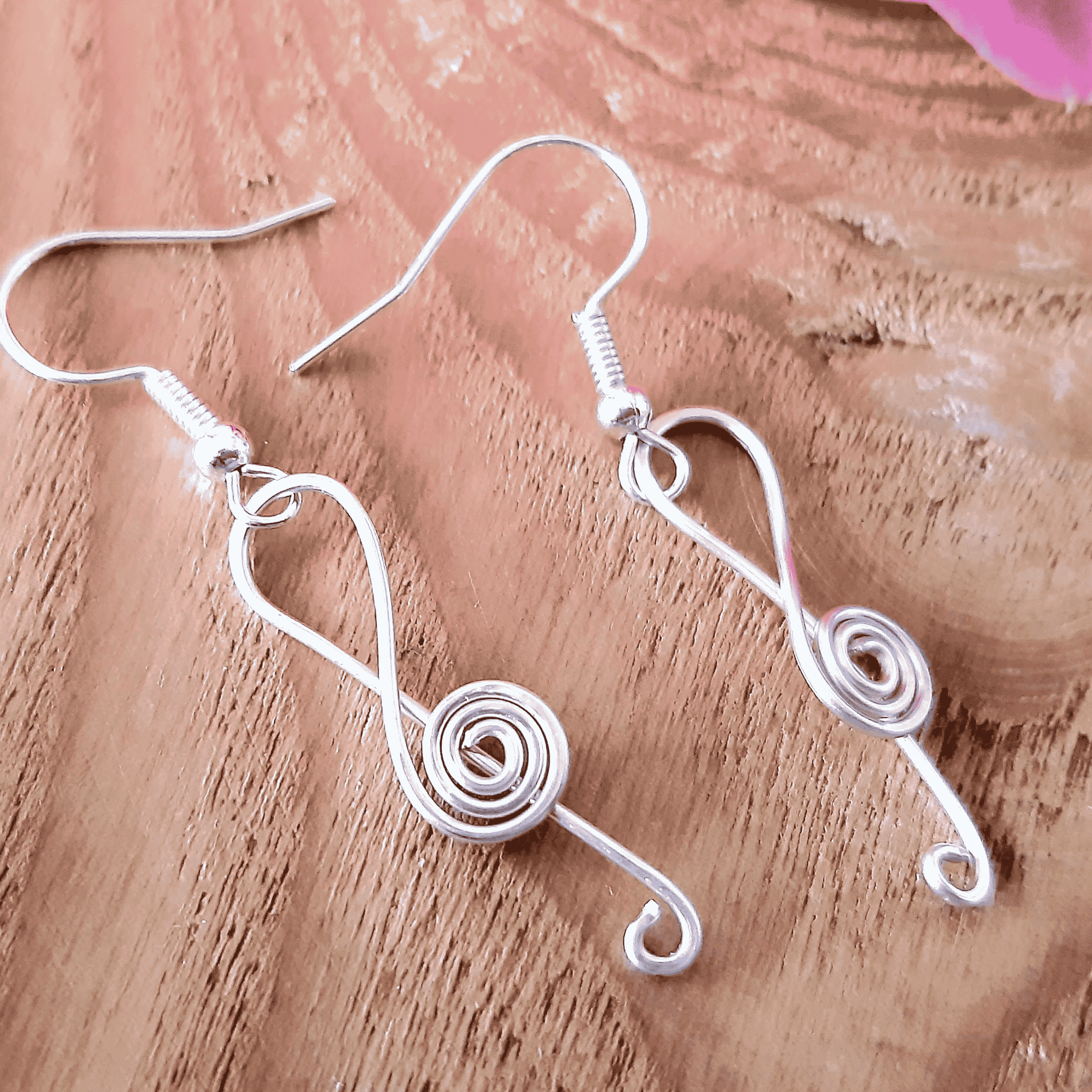 Silver wire music note earrings on a wooden surface